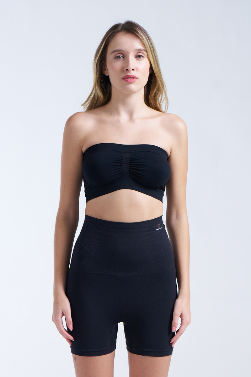 Woman wearing a black strapless top and high-waisted shorts on a white background