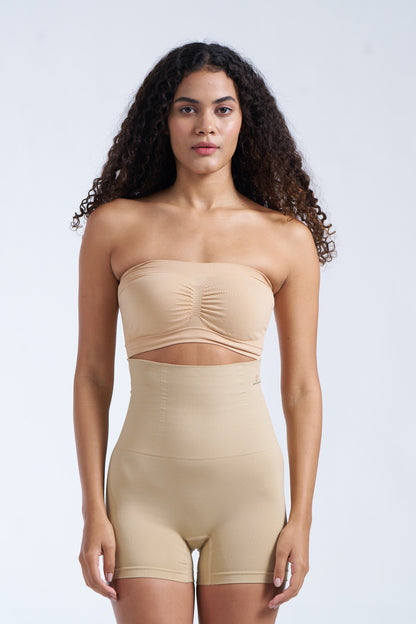 A model wearing beige tummy and thigh shorts with a strapless top.