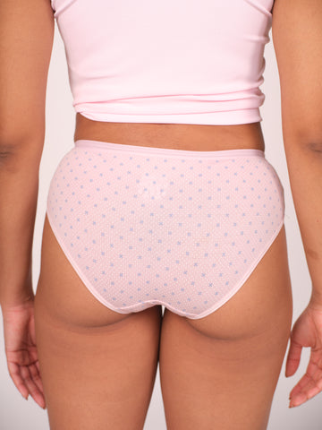 Person wearing light pink polka dot underwear and a matching top on a plain background