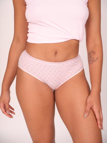 Person wearing light pink polka dot underwear and a matching top on a plain background